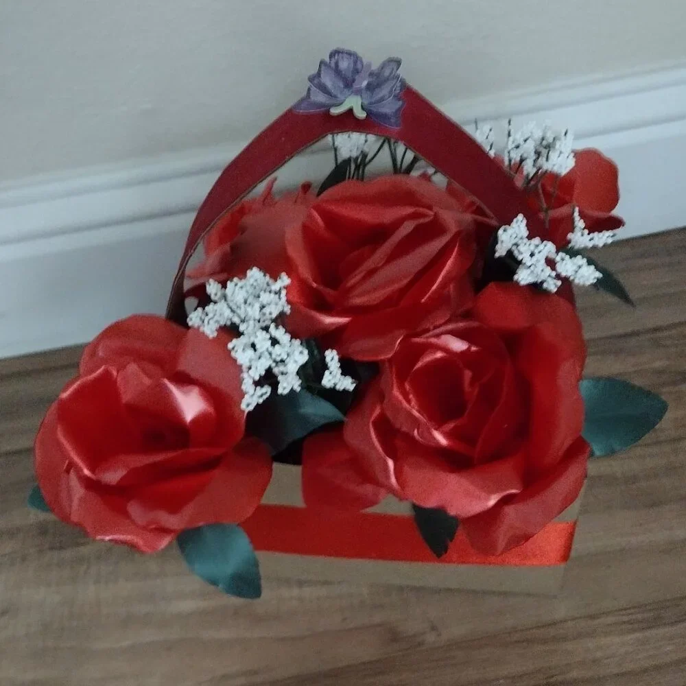 Handmade floral arrangement with plastic ribbon roses.